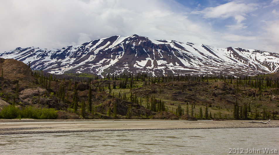 Snow covered mountains, green forest, silvery river, blue and white sky; Earth's rainbow.