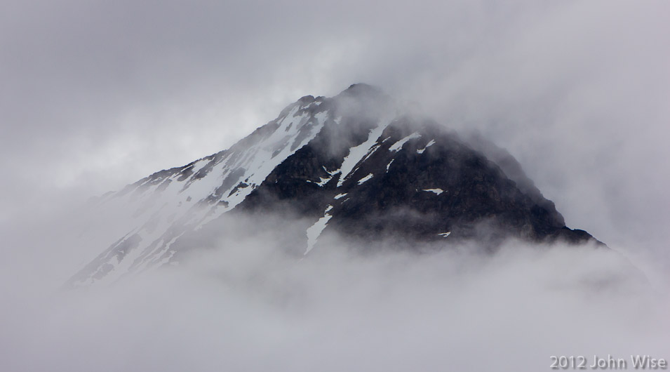 Mountain peaking through the clouds on the Alsek River in the Yukon, Canada